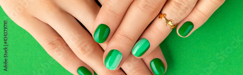 Beautiful groomed woman's hands with spring summer nail design on green background