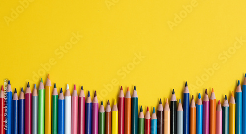 Colouring pencils isolated on yellow background close up concept with copy space for text 