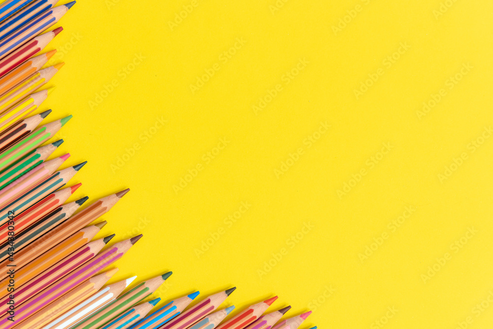 Fototapeta premium Colored pencils isolated on yellow background close up concept with copy space for text 