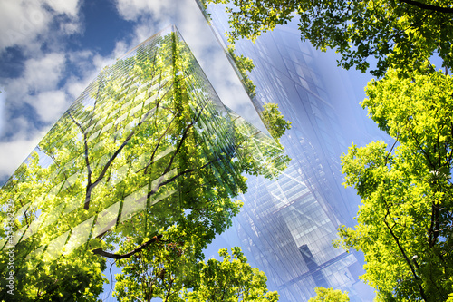 green city - double exposure of lush green forest and modern skyscrapers windows. photo