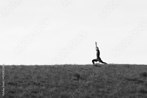 young athletic looking man in black sprosts clothes doing yoga outside