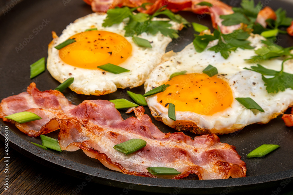 fried eggs with bacon and herbs close up