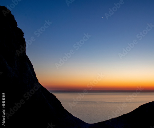 Beautiful sunset over sea with silhouette of rock