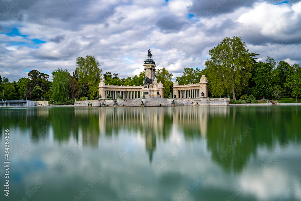 Estanque del Retiro vacío en un día soleado con nubes y efecto seda en el agua verde, lago del parque del Buen Retiro