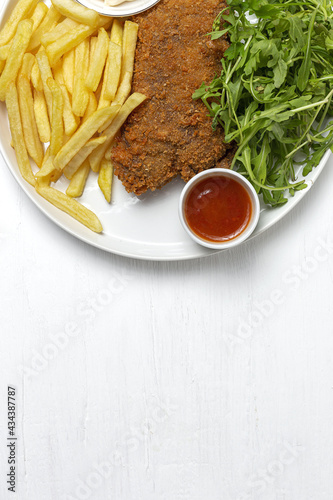 Homemade traditional Milanese veal escalope with french fries photo