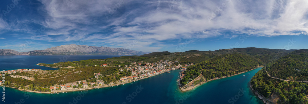POVLJA, CROATIA - August 2020: Beautiful village Povlja on island Brac with mountain Mosor in background. Panoramic view. Aerial drone shot.