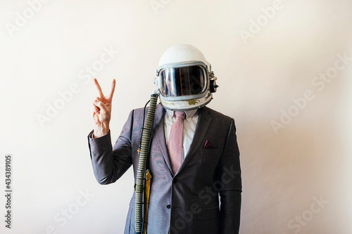 Quadro em tela Businessman with astronaut helmet showing fingers in V shape