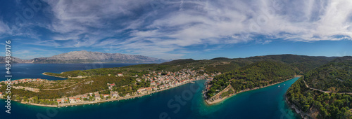 POVLJA, CROATIA - August 2020: Beautiful village Povlja on island Brac with mountain Mosor in background. Panoramic view. Aerial drone shot.