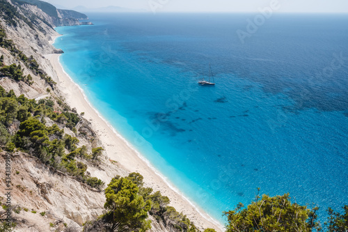Lefkada, Greece. Remote white Egremni beach with lonely luxury yacht boat on the turquoise colored bay on Ionian Sea
