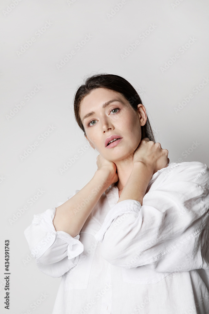 Young caucasian woman, wears white shirt, posing at the studio. Vertical. Young caucasian woman, wears white shirt, posing at the studio. Vertical.