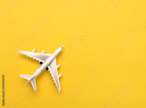 The white plane lies on a yellow background. Travel concept. © Mi_Lara