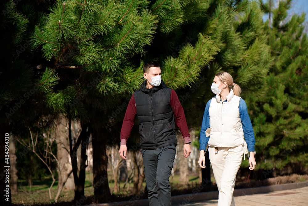Fototapeta premium Young European man and woman in protective disposable medical mask walking outdoors afraid of dangerous NCoV 2019 influenza coronavirus mutated and spreading in China