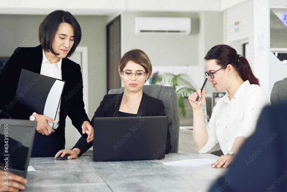 Three young successful business women in the office working together on a project