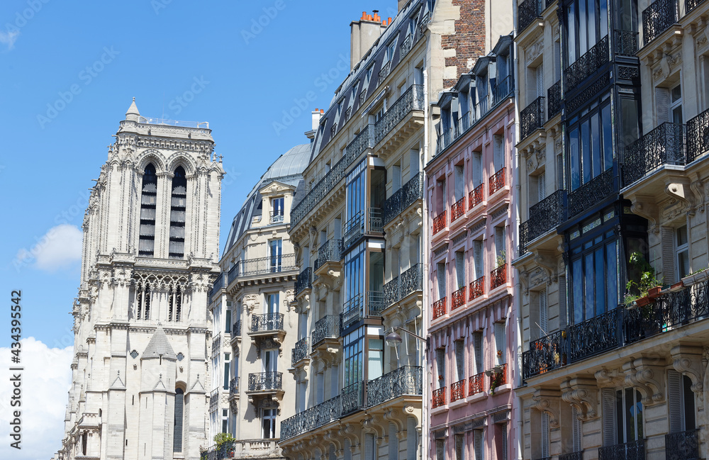 Traditional facades of French houses with typical balconies and windows with Notre Dame cathedral towers in the background. Paris.