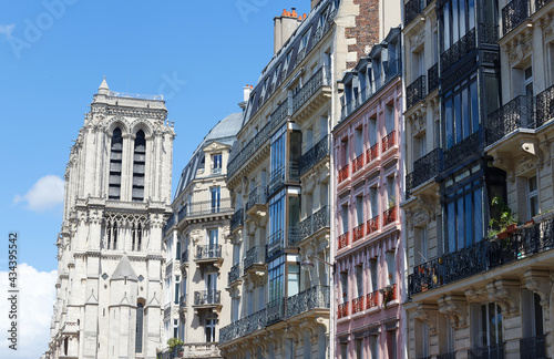 Traditional facades of French houses with typical balconies and windows with Notre Dame cathedral towers in the background. Paris.