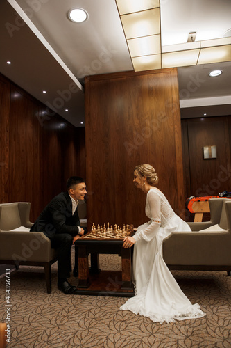 The bride and groom play chess before the ceremony. Newlyweds in the hotel. Morning before the wedding.