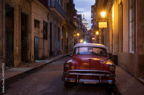 Fototapeta Naklejka Na Ścianę i Meble -  Amazing old american car on streets of Havana with Capitolio Building in background during night. Havana, Cuba.