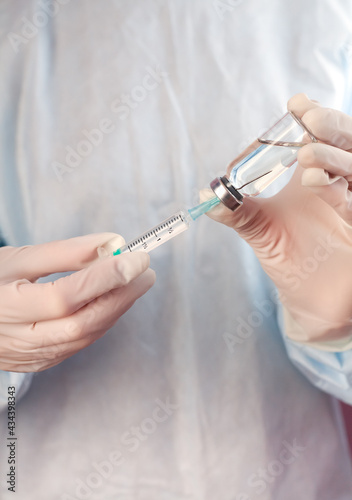 Nurse holding syringe and vaccine vial in hands. Coronavirus and influenza vaccination. Close-up. © Markoff