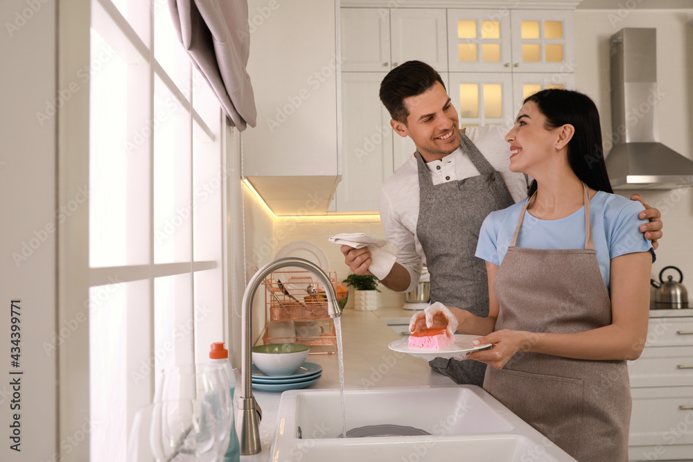Happy lovely couple washing dishes in kitchen Happy lovely couple washing dishes in kitchen
