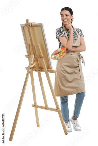Young woman with drawing tools near easel on white background
