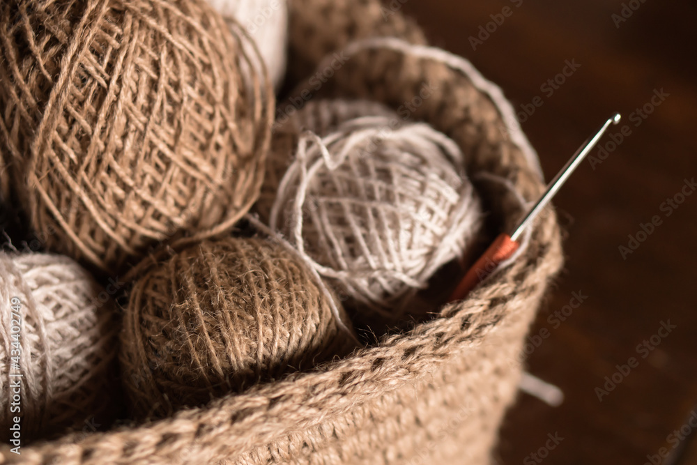 close up: knitted basket with balls of jute threads and crochet hooks on table
