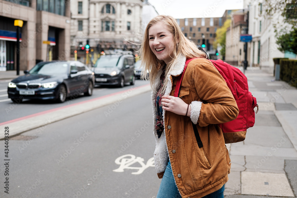 Fototapeta premium Young blonde woman crossing the road and smiling.