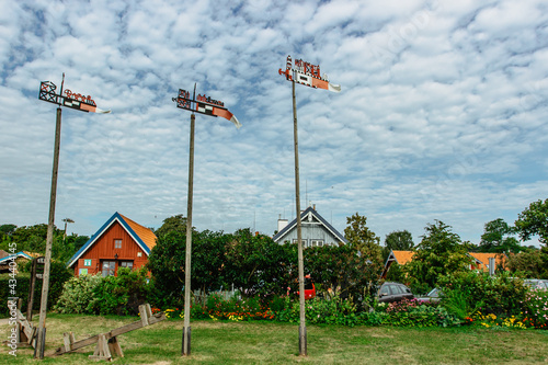 Nida,resort town in Lithuania located on the Curonian Spit. Traditional colorful wooden carved weathercocks typical houses in background.Weather vanes show wind direction and identify fisherman boat © Eva
