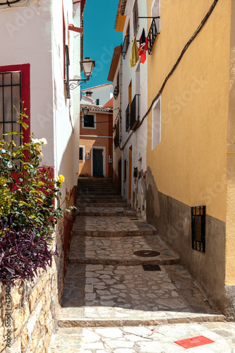 Finestrat, Alicante province, Spain. Beautiful quiet narrow street of small Finestrat village old town with old buildings, stone pavement at sunny day
