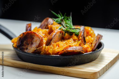 Traditional Polish dish called bigos made of sauerkraut, sausage and mushrooms, food served warm in a cast iron pan