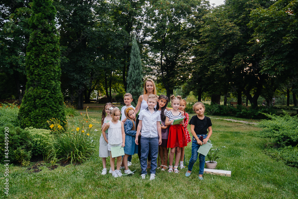 Obraz premium A teacher teaches a class of children in an outdoor Park. Back to school, learning during the pandemic
