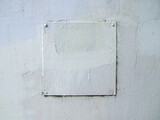 An unevenly painted old gray wall with an attached plate in the middle. Object in small and large cracks. Copy space. 