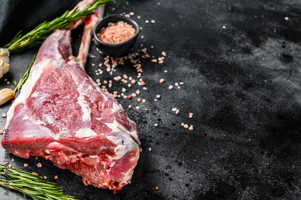 Whole lamb leg. Raw organic meat. Black background. Top view.  Copy space
