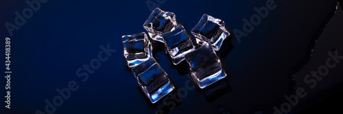 Wet ice cubes on blue background top view