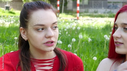 Two beautiful Girls smoking Iqos electronic Cigarette in Summer Park