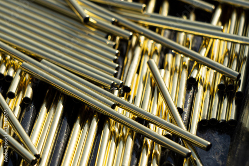 A bunch of identical brass pipes. The polished brass rods shine in the sun. Alloy details.