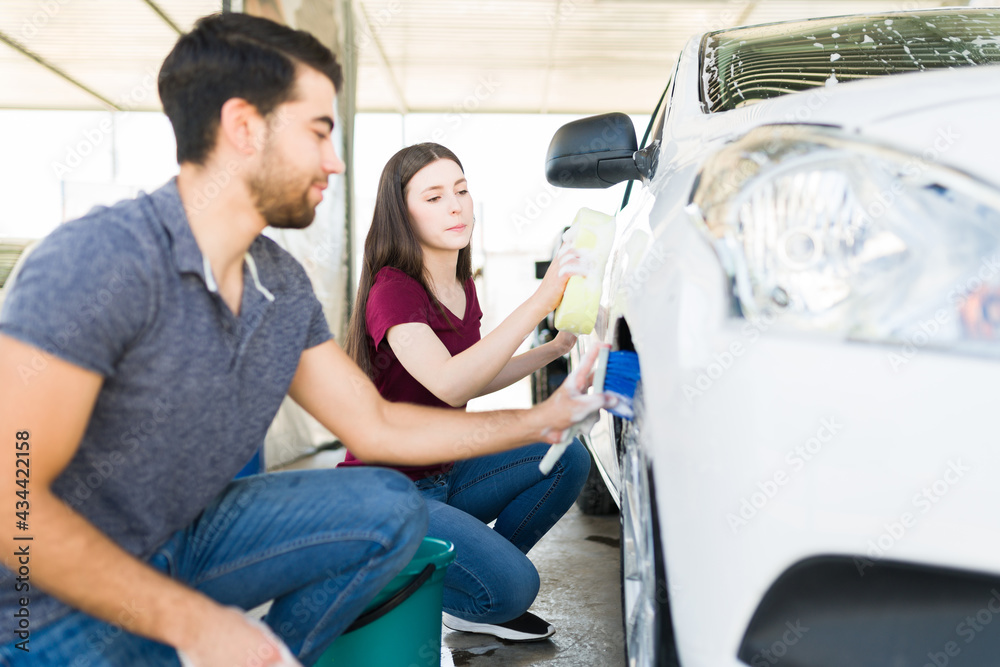 Girlfriend helping her boyfriend wash the car Girlfriend helping her boyfriend wash the car