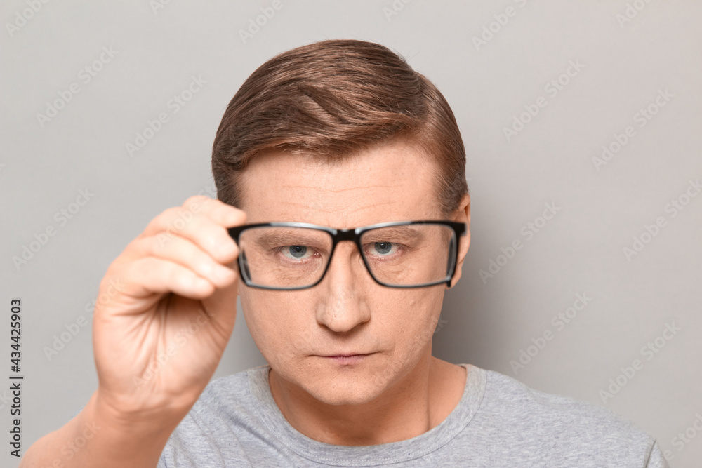 Portrait of serious man peering through glasses at something Portrait of serious man peering through glasses at something