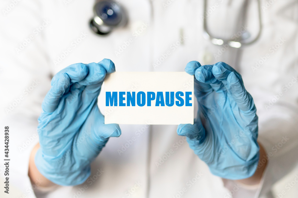 A medical worker in gloves holds a card with the words MENOPAUSE. Medical concept. A medical worker in gloves holds a card with the words MENOPAUSE. Medical concept.