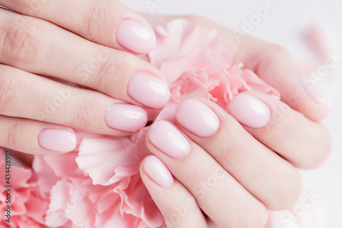 Close-up beautiful sophisticated woman hands with pink flowers on white background. Concept manicure hand care spa  top view