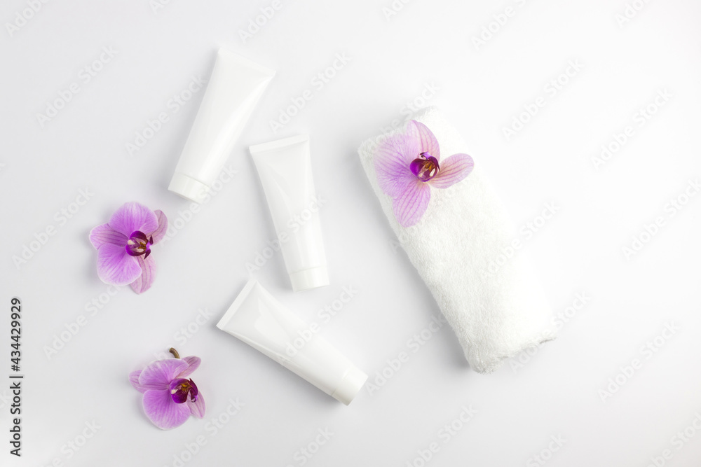 Cosmetic mock-up. White tubes with cream or lotion and a white towel next to it. Treatment in the spa salon. Cosmetic procedures. Copy space Cosmetic mock-up. White tubes with cream or lotion and a white towel next to it. Treatment in the spa salon. Cosmetic procedures. Copy space
