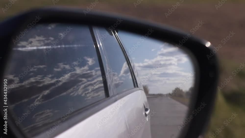 close up of motioned view in car rear view side mirror of clouds and field. Travelling by car concept. close up of motioned view in car rear view side mirror of clouds and field. Travelling by car concept.
