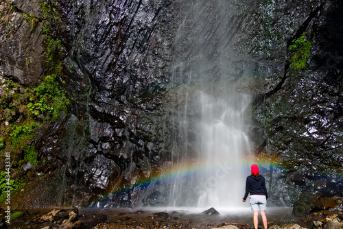 Cascade du Queureuilh au mont dore en pose longue avec présence d'une personne devant la cascade et un arc en ciel