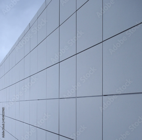 geometric blue metallic cladding modern facade in perspective view with blue sky