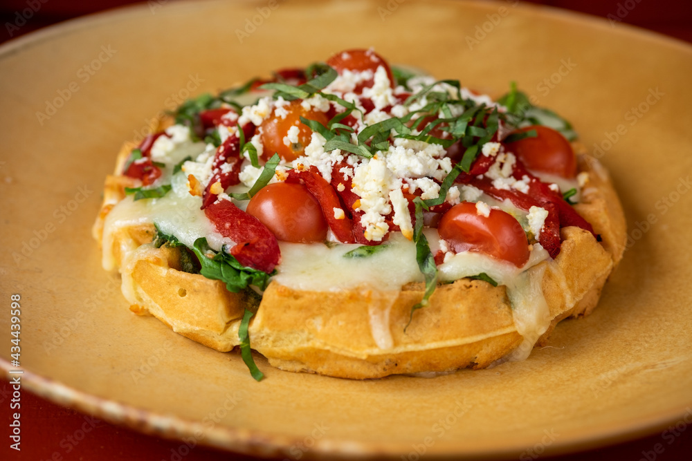 Waffle with tomato, basil, mozzarella, roasted bell peppers, and feta cheese.
