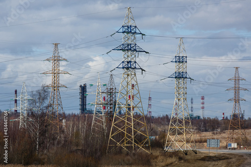 Electricity pylons against the constructions of oil refinery in the early  spring. High voltage power line supports or posts. Transmission towers of electric power lines in Yaroslavl region, Russia