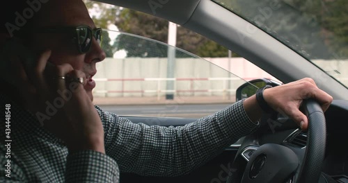 Wallpaper Mural A man with glasses is talking while driving a car in motion. He speaks the message, pins the phone. Holds the steering wheel with his hands. Torontodigital.ca