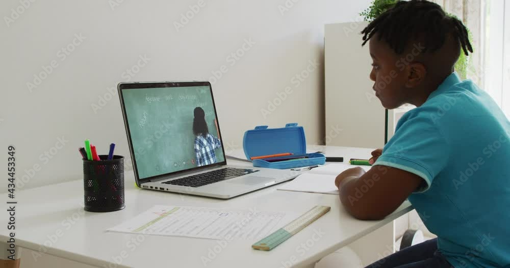 African american boy having a video call on laptop while doing homework at home African american boy having a video call on laptop while doing homework at home