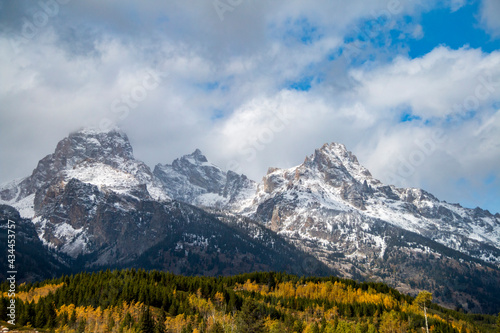 dramatic snow capped mountain peaks of the Grand teton mountain range and colorful autumn foliage in Jackson, Wyoming.