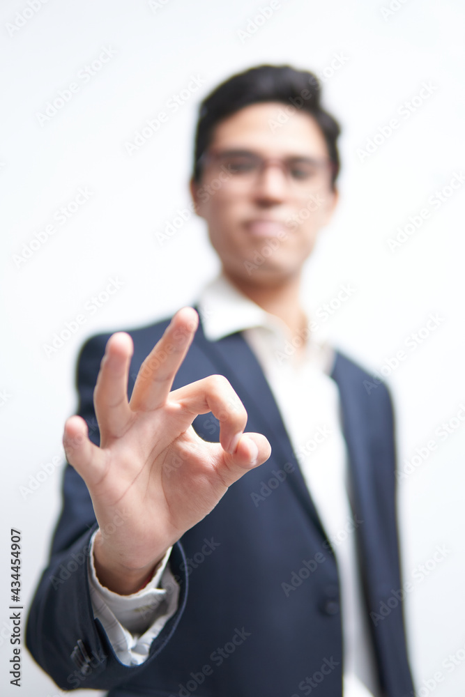 young latin man in suit making an approval sign with unfocused hand