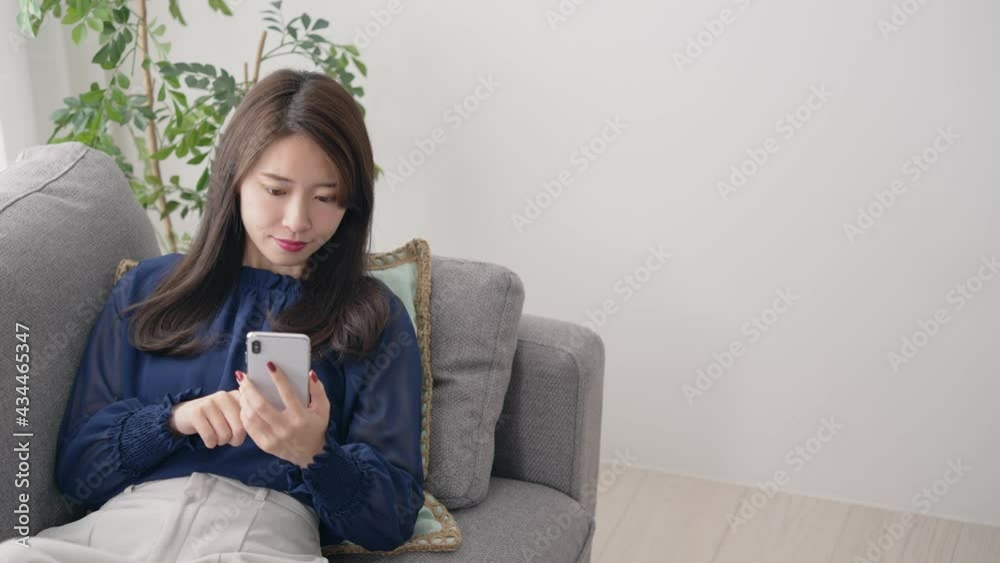 部屋でリラックスしてスマホを見る女性　スローモーション